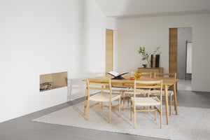 Matgrupp i ljust trä med fyra stolar i minimalistisk matsal med öppen spis och betonggolv