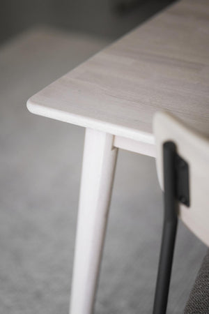 Vit träpall med rundad sits och smala ben, närbild på hörn och trästruktur