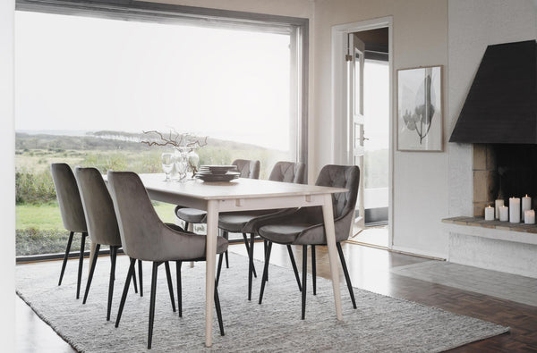 Matgrupp med ljust bord och grå sammetsstolar i modern matsal med utsikt över natur