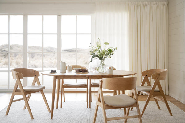 Matbord i ljust trä med matchande stolar i skandinavisk design vid fönster med naturvy