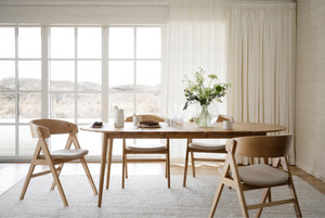 Matbord i ljust trä med matchande stolar i skandinavisk design vid fönster med utsikt
