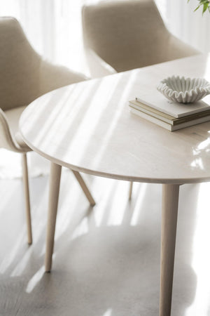 Runt vitt matbord med träben och moderna designstolar i ljust nordiskt hem