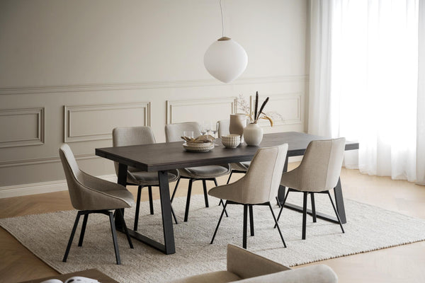 Modern matgrupp med mörkgrått bord och sex beigeklädda stolar i ljus matsal med pendant-lampa