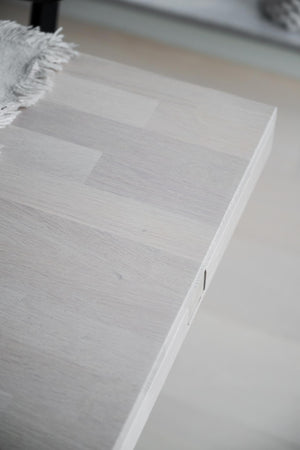 Ljust trägolv i ek med vit yta och synlig trästruktur, närbild på hörn med vitlist