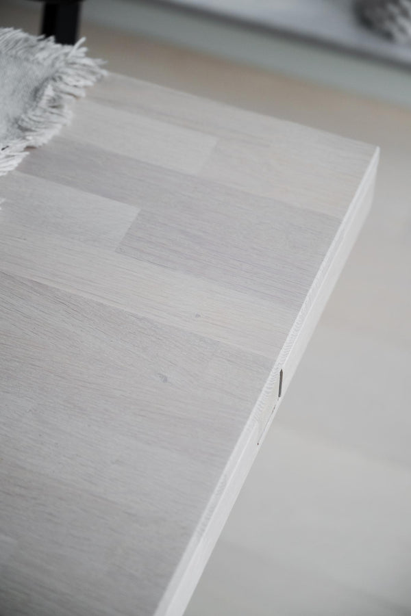 Ljust trägolv i ek med vit yta och synlig trästruktur, närbild på hörn med vitlist