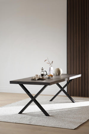Matbord med kryss i svart metall och mörkgrå skiva, dukat med kaffepress och vaser i minimalistisk stil