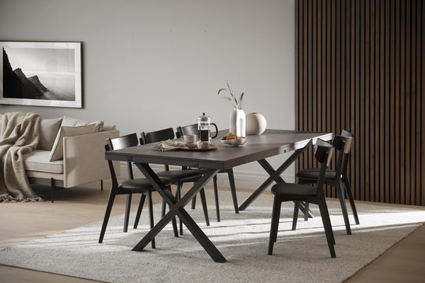 Modern matgrupp med svarta stolar och mörkt bord med kryss-ben i skandinavisk inredning