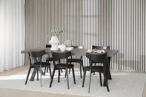 Matbord i grått trä med sex svarta stolar i modern skandinavisk stil mot randig vägg