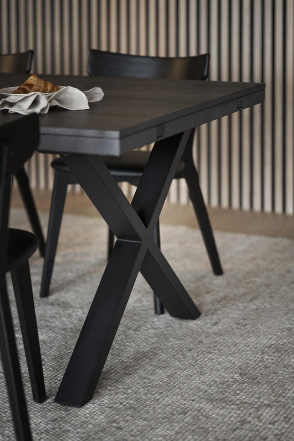 Matbord i svartbetsad ek med korsben och matchande stolar i modern skandinavisk design