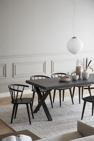 Matbord i svart trä med korsben och matchande svarta stolar i skandinavisk design