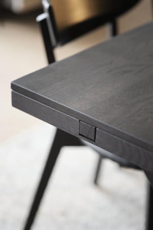 Detaljbild av svart skrivbord med trästruktur och liten låda, moderna metallben