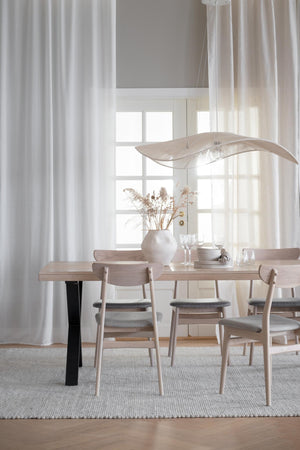 Matgrupp i ljust trä med gråa stoppade stolar, skandinavisk design i ljus matsal med gardin och pendant lampa