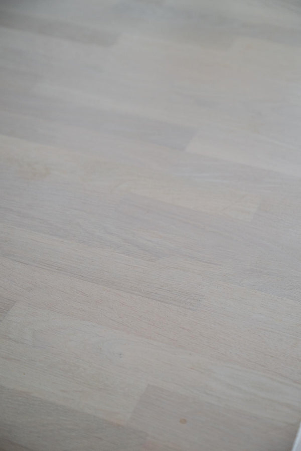 Närbild av ljust trägolv med naturlig textur och ådring i vit eller ljusgrå ton