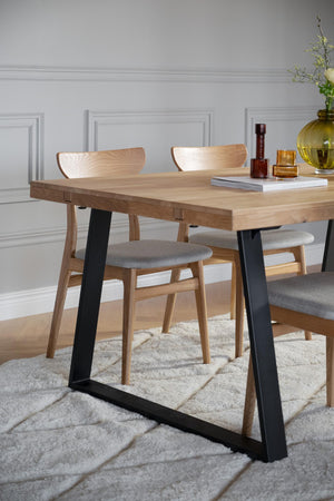 Matbord i ek med svarta metallben och stolar med grå klädsel på vit matta i ljust rum