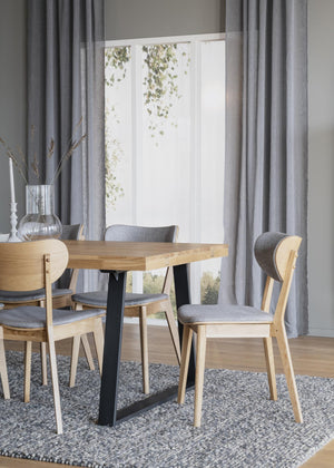 Matgrupp med träbord på svarta ben och fyra stolar med grå klädsel i ljus matsal med gardiner