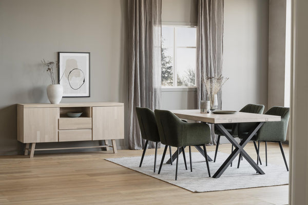 Matgrupp med ljust bord, gröna stolar och matchande skänk i modern skandinavisk matsal