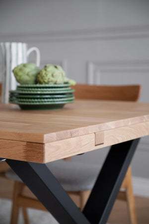 Matbord i massiv ek med svarta korsben och synlig skarv i bordsskivan