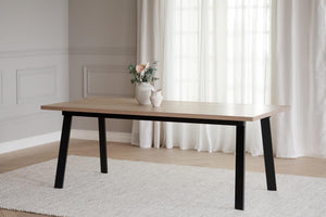 Matbord med ljus träskiva och svarta ben i modern skandinavisk design på ljus matta