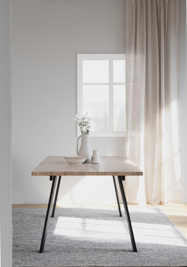 Matbord i ljust trä med svarta metallben i minimalistisk skandinavisk stil med vita keramikaccessoarer