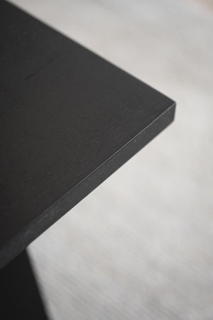 Närbild på svart träbordsskiva med synlig struktur och kant mot vit bakgrund