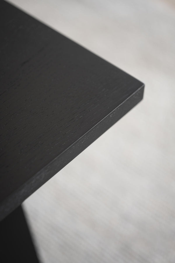Närbild på svart träbordsskiva med synlig struktur och kant mot vit bakgrund