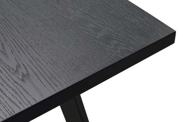 Närbild av svart träbordsskiva med synlig trästruktur och massiv svart metallbas