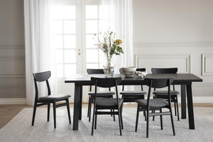 Svart matbord med matchande stolar i modern skandinavisk stil, ljust matrum med franska dörrar