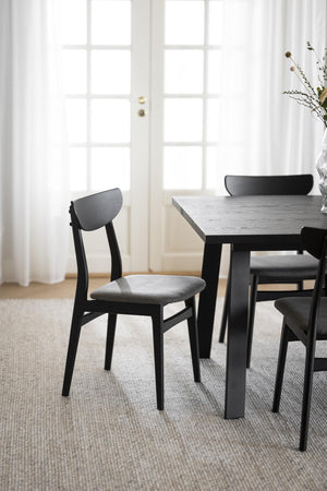 Svart matstol med grå stoppad sits vid matbord i modern skandinavisk matsal