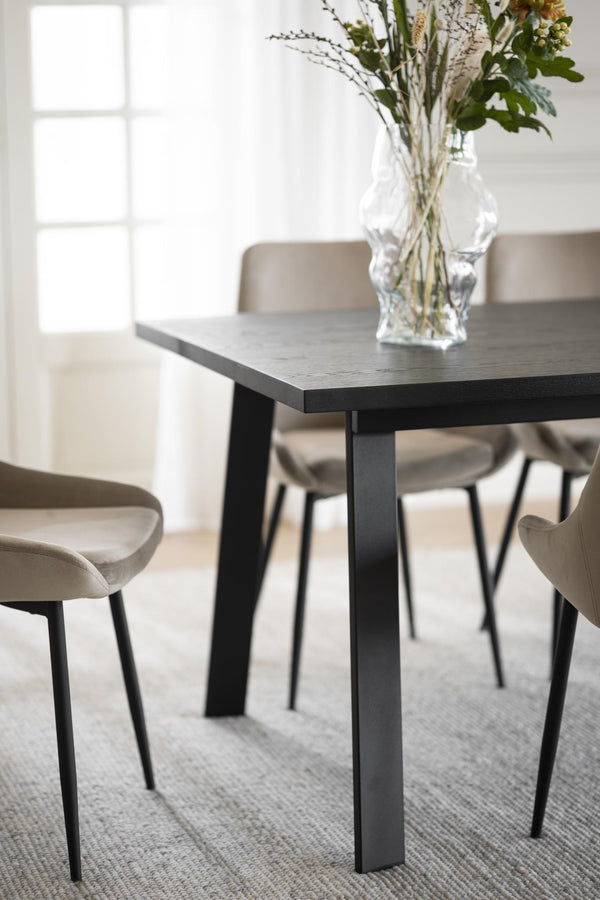 Matbord i mörkt trä med svarta ben och beige stolar i modern skandinavisk matsal