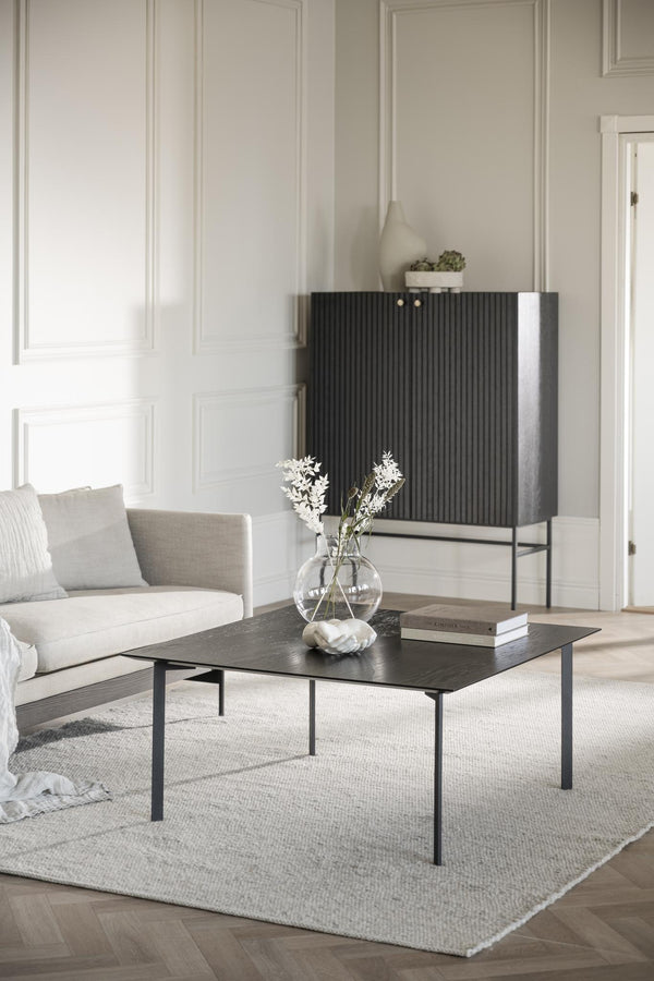 Soffbord i svart ek med stilren design och smala metallben i modernt vardagsrum med beige inredning