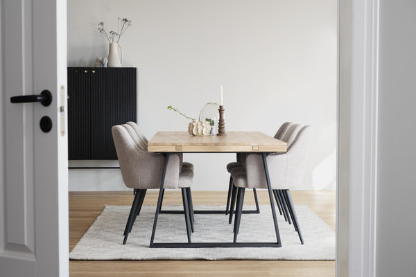 Matbord i ljust trä med fyra grå stolar på vit matta i modern matsal med minimalistisk inredning