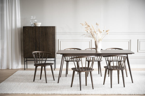 Matgrupp i mörkt trä med sex stolar och skänk i modern skandinavisk stil på ljus matta