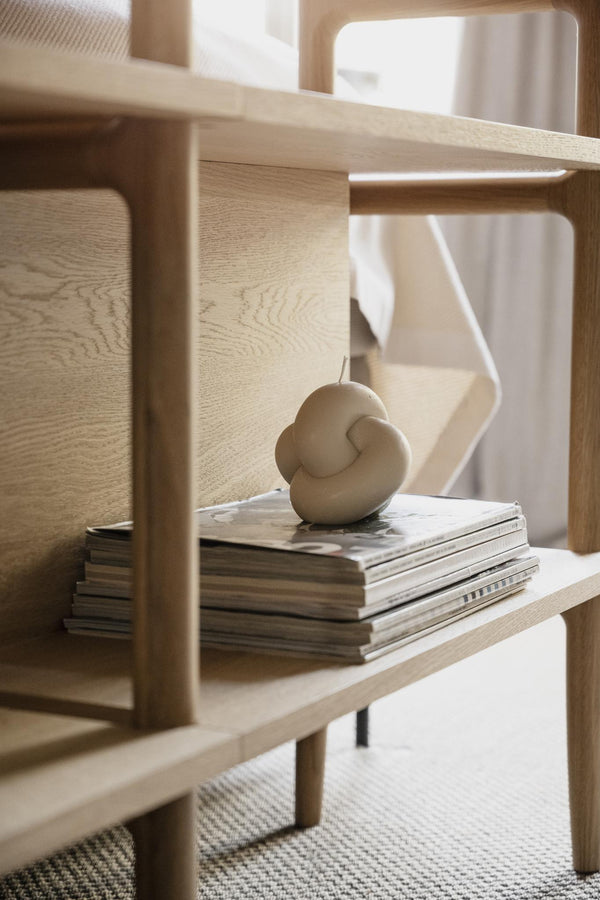 Ljust träsoffbord med staplade tidningar och beige dekorationsljus i modern skandinavisk stil