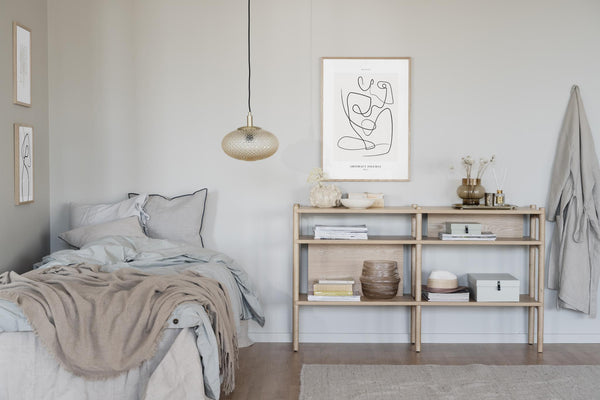 Scandinaviskt sovrum med ljust trähylla, abstrakt väggkonst och beige textilier i naturliga toner