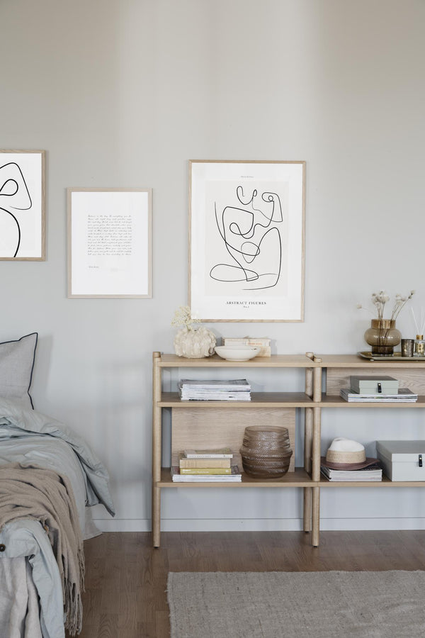 Ljust sovrum med abstrakt konst på väggen och ljust trä förvaring med böcker och dekorationer