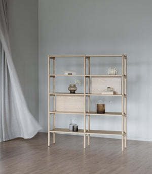 Ljus trähylla i ek med öppna fack och dekorativa vaser mot grå vägg i minimalistisk inredning