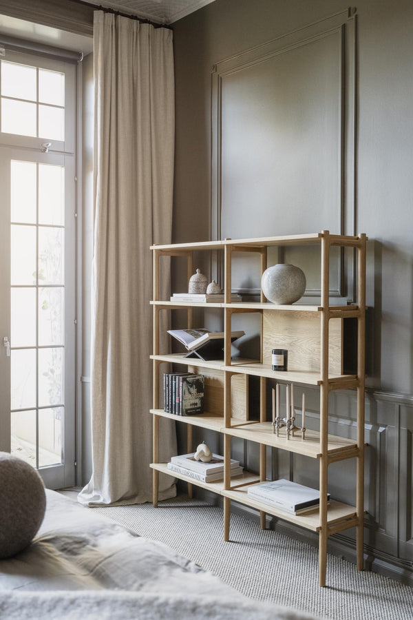 Ljus träbokhylla i naturligt trä med öppna fack, dekorerad med böcker och prydnadssaker i minimalistiskt vardagsrum