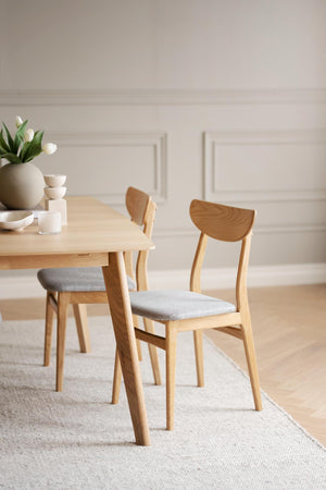 Ljusa matstolar i ek med grå stoppade sitsar vid matbord i skandinavisk design