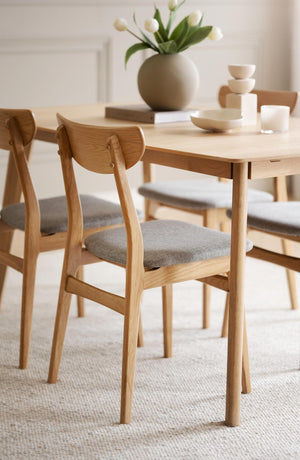 Matbord i ljus ek med matchande stolar och grå dynor i skandinavisk minimalistisk stil