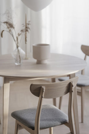 Ljust matbord i trä med stolar med grå dynor i skandinavisk minimalistisk inredningsstil