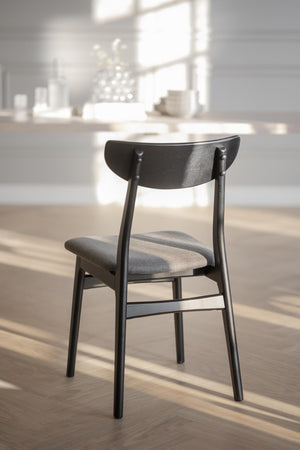 Svart trätstol med grå stoppad sits i modern matsal med ljusinsläpp från fönster