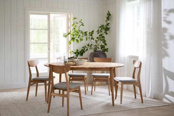 Matbord i ek med sex stolar i ljust matrum med trägolv och vita väggar