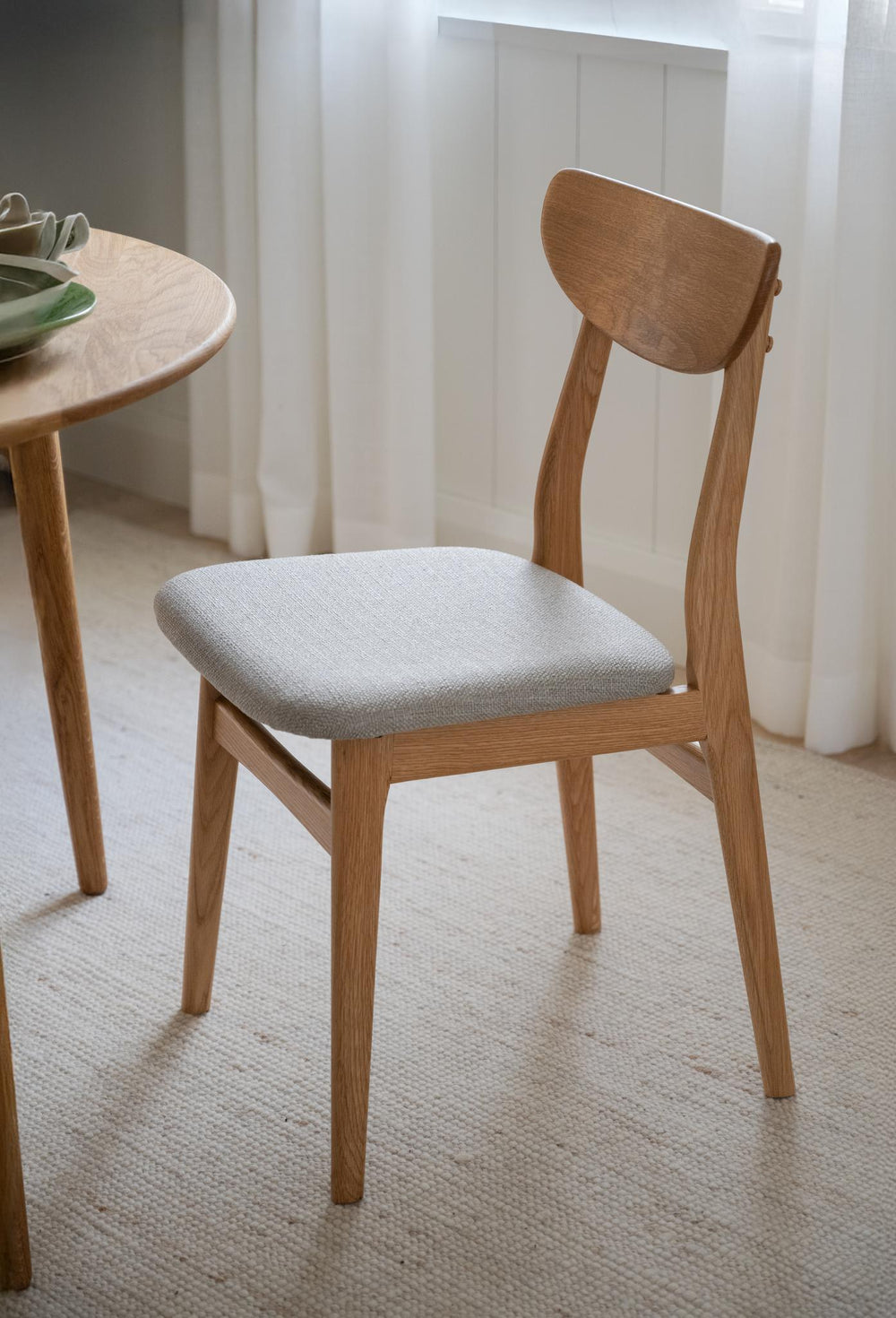 Stol i ljust trä med grå stoppad sits och halvmåneformad rygg i skandinavisk design