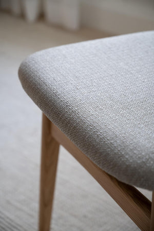 Närbild på grå linneklädsel på träpall med trästomme i ljus ek