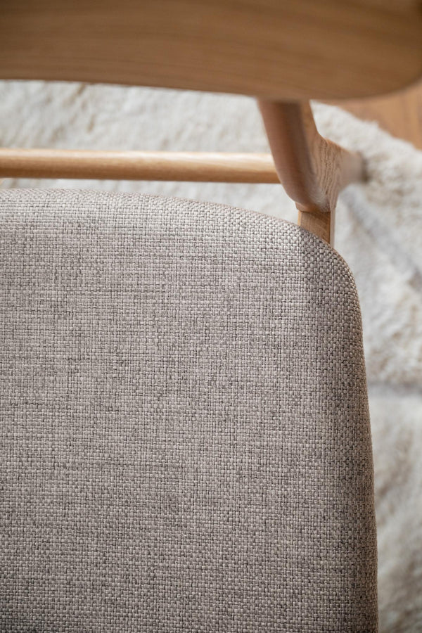 Närbild av stol med beige linneklädsel och träram, skandinavisk design med naturliga material