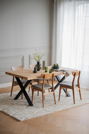 Matbord i ljust trä med svarta korsben och fyra stolar i modern skandinavisk design på ljus matta