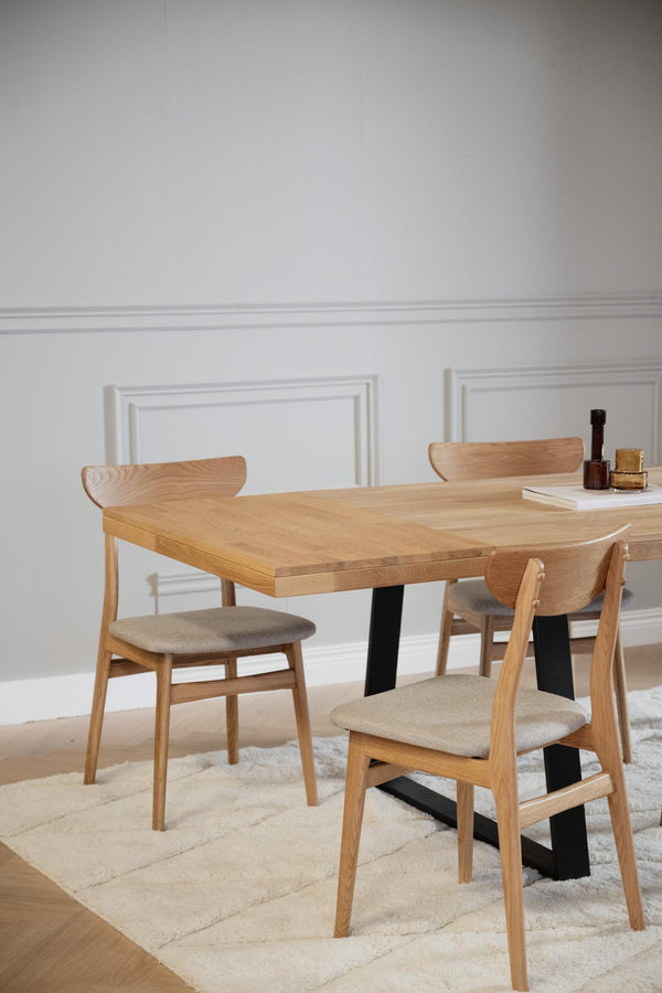 Matbord i ek med svarta ben och fyra stolar med beige stoppad sits i modern skandinavisk stil