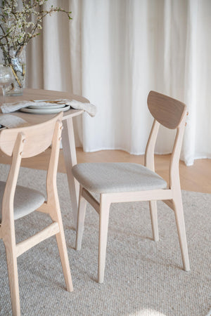 Ljusa trässtolar med grå stoppad sits vid runt matbord i skandinavisk stil