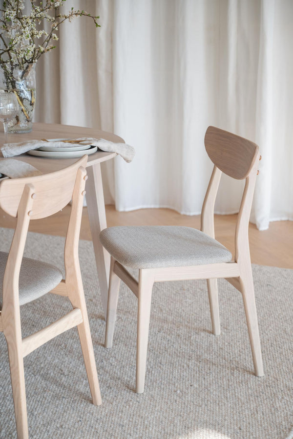 Ljusa trässtolar med grå stoppad sits vid runt matbord i skandinavisk stil