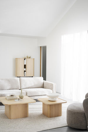 Minimalistiskt vardagsrum med beige soffa, ljusa träbord och naturliga toner i skandinavisk stil